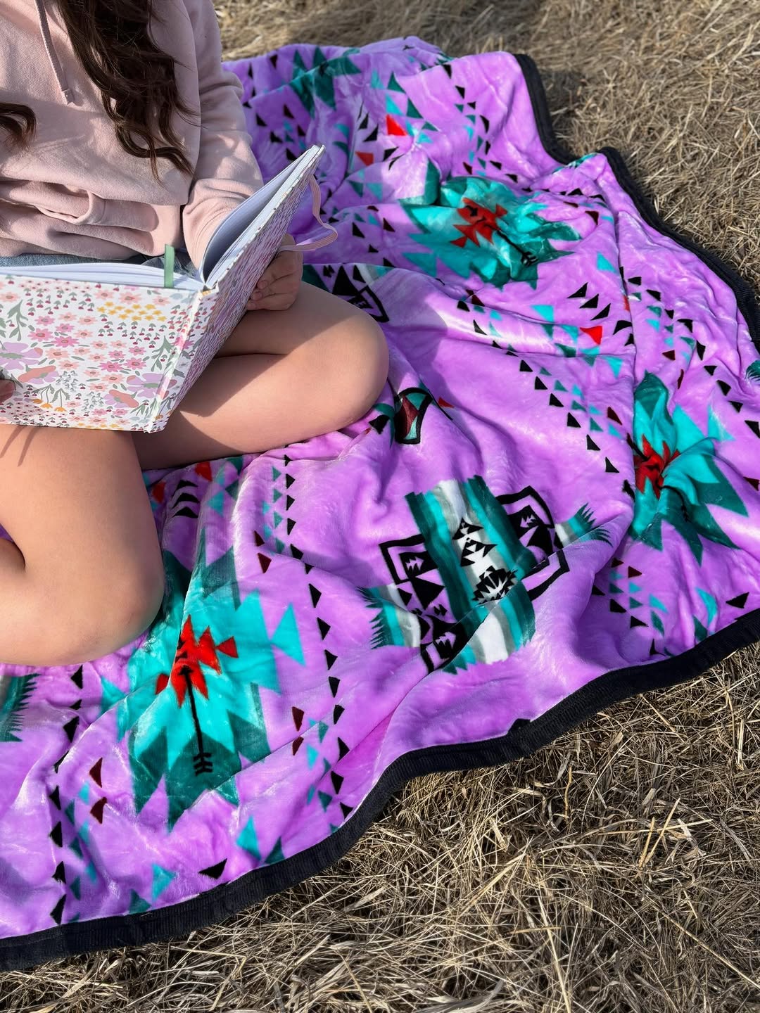 Person reading on a purple GS Blanket outdoors